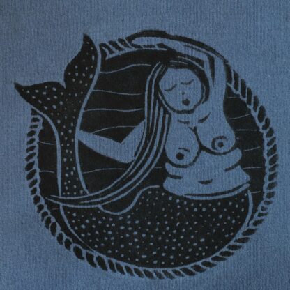 Detailaufnahme eines Linoldruckes, der eine dicke Meerjungfrau mit großen Brüsten zeigt, auf einem blauen Stoff
