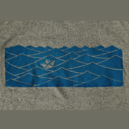Linoldruck eines Papierbootes auf grauem Textil