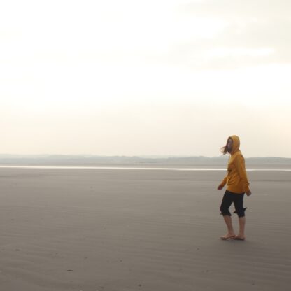Frau am Strand mit gelbem Hoodie