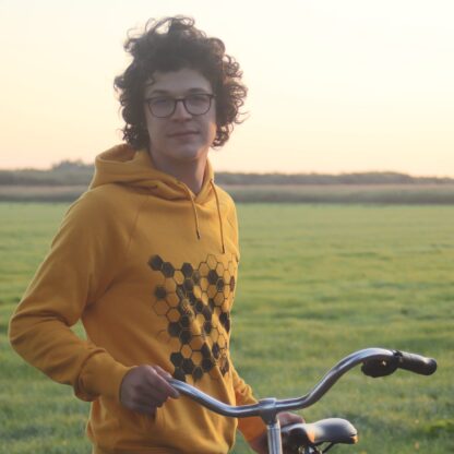 Handbedruckter sonnengelber Hoodie mit Honigwaben als Motiv, Mann mit Fahrrad vor grüner Landschaft