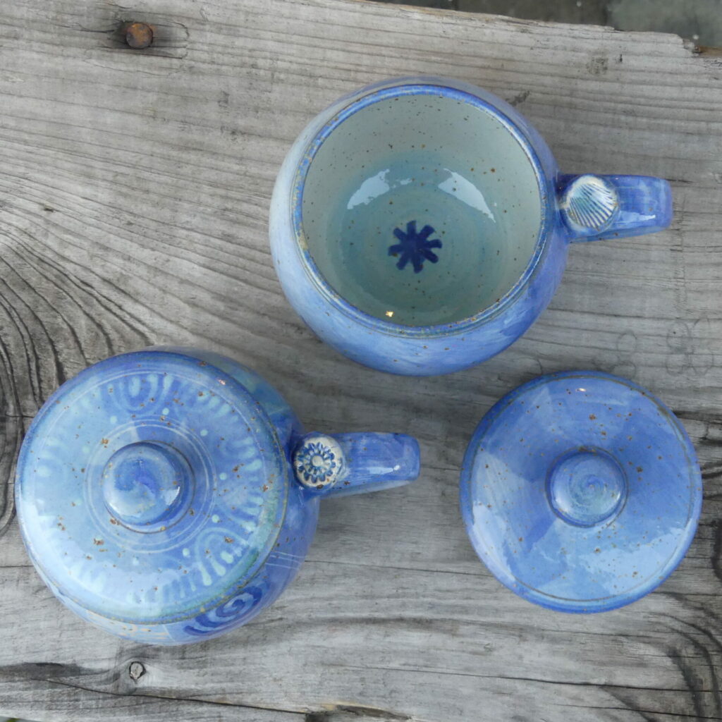 Kugel-Keramiktasse mit Deckel mit blauem Dekor von oben auf Holzbank