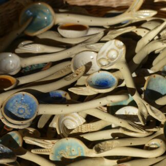 Viele kleine Löffel aus Keramik mit verschiedenen Muschelabdrücken und anderen Motiven. Naturton, im Löffel blau, türkis, weiß
