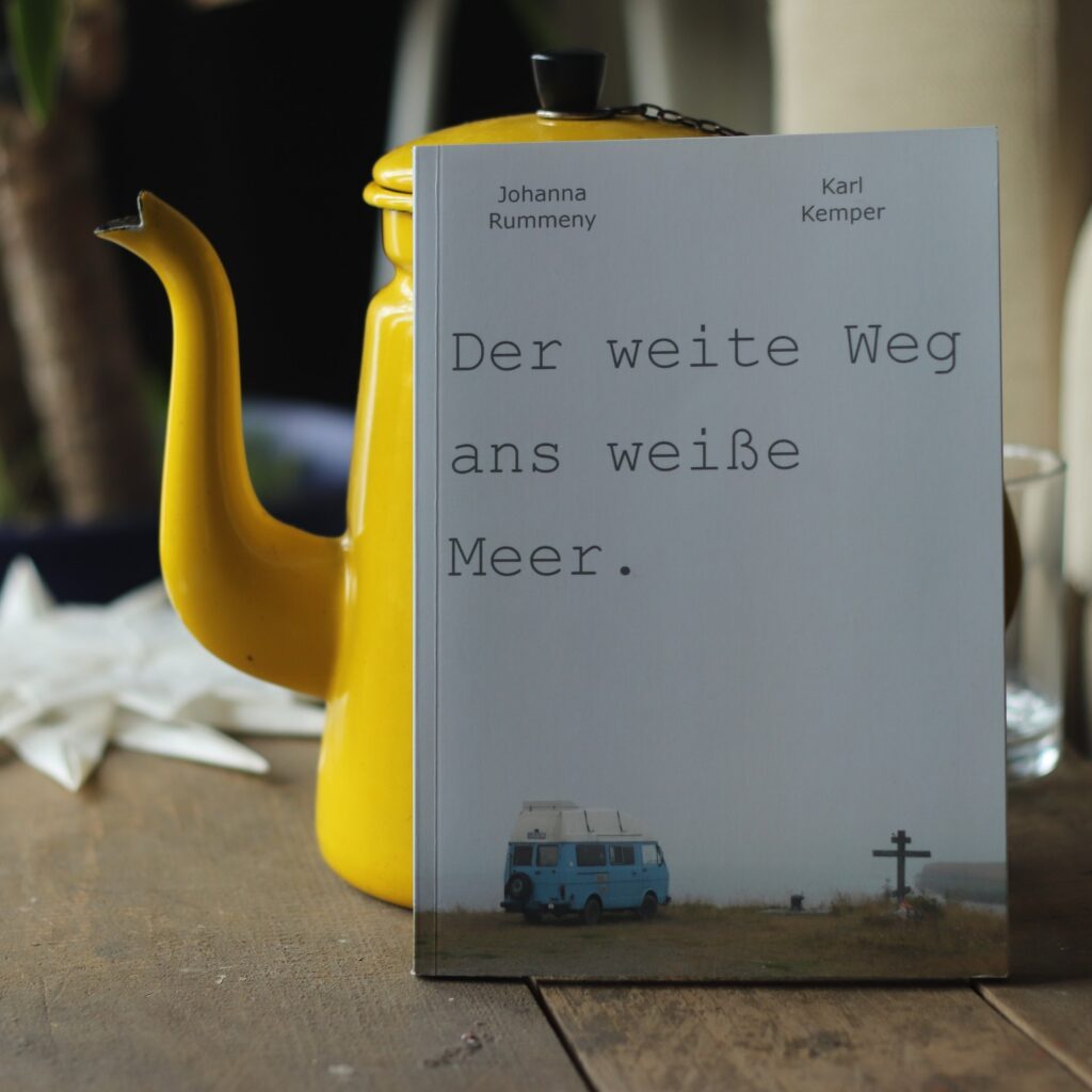 Buch mit dem Titel Der weite Weg ans Weiße Meer. vor einer gelben Teekanne, Autoren Karl Kemper und Johanna Rummeny